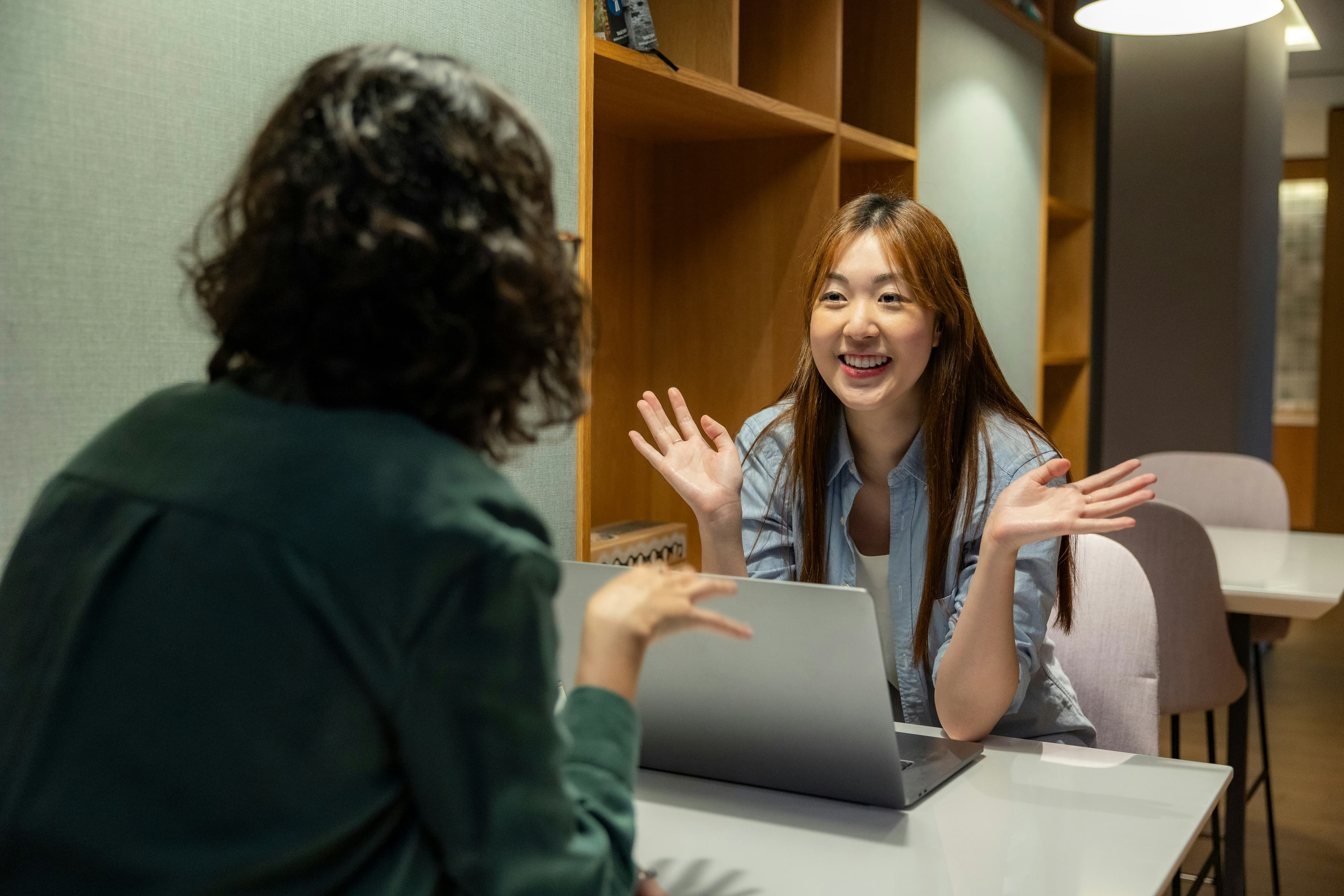 Two professionals having an engaged conversation about learner outcomes across a desk with a laptop
